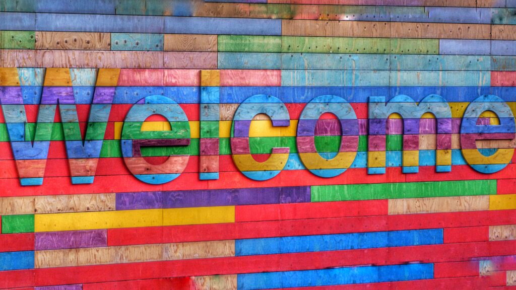 wood boards painted blue, green, purple, and yellow with wood letters spelling out the word welcome