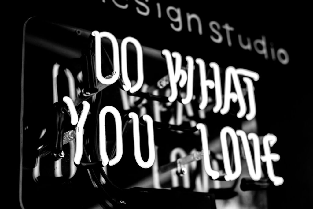 a neon sign with white lettering saying do what you love with a black background