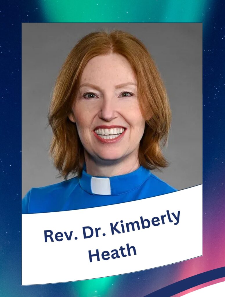 a woman with red shoulder length hair, smiling, wearing a blue shirt with a white clergy collar